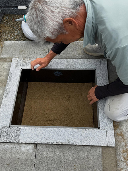 四神と経文を彫刻したプレートを設置している墓石職人