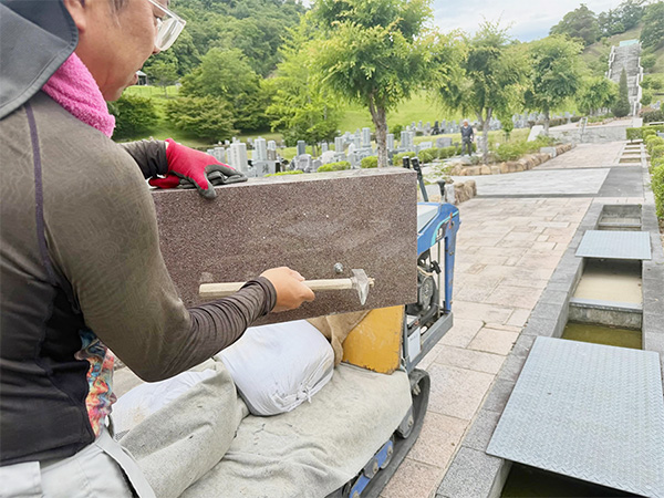 宝塚すみれ墓苑で巻石を固定するための石材固定金具を打ち込んでいる写真
