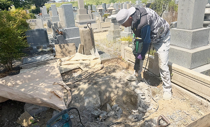 兵庫県尼崎市の弥生ケ丘墓園で地中に埋まった間知石をハツリ道具で解体している写真